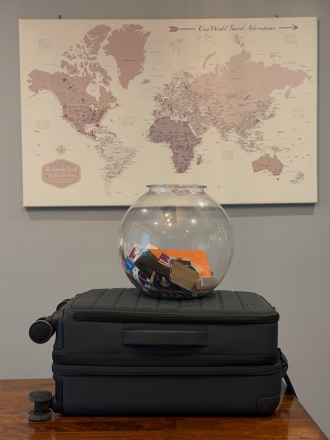 Navy suitcase, a bowl of hotel keys and cruise wristbands, and the Kennedy Family world pin map